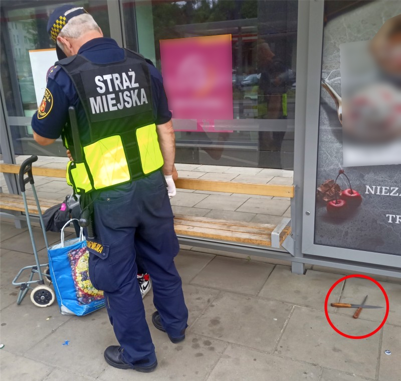 Strażnik miejski na przystanku, przy którym ujęto mężczyznę. Z prawej strony, na ziemi, leżą noże, które ujęty miał przy sobie.