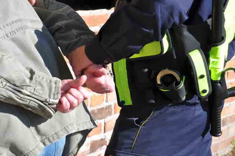 Strażnik miejski zakuwający mężczyznę w kajdanki- zdjęcie ilustracyjne