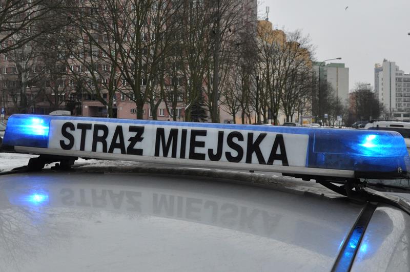 Radiowóz straży miejskiej na tle warszawskiego bloku.