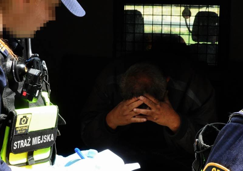 Strażnik miejski zamykający mężczyznę w przedziale przewozowym radiowozu- zdjęcie ilustracyjne