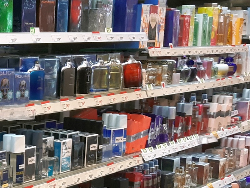 Zdjęcie ilustracyjne: półka w drogerii z wystawionymi flakonami perfum.