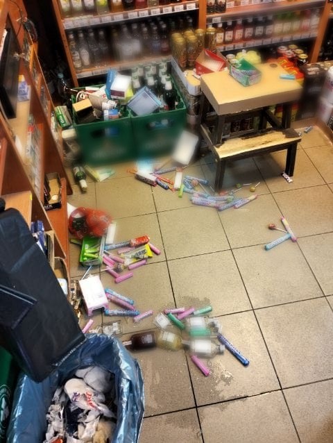 Wnętrze sklepu, zdemolowanego przez uczestników bójki. Porozrzucane butelki na podłodze. Oryginalne zdjęcie z interwencji.