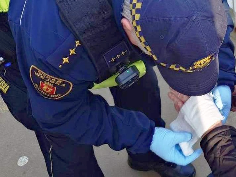 Strażnik opatrujący rękę starszemu mężczyźnie
