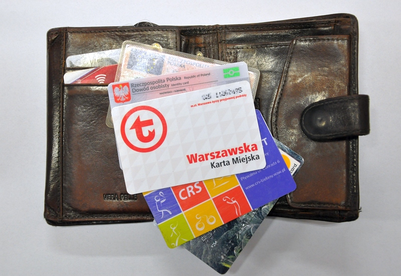 Zdjęcie ilustracyjne: męski portfel, na nim wachlarzyk dokumentów: karta miejska, prawo jazdy, dowód osobisty, karta bankomatowa.