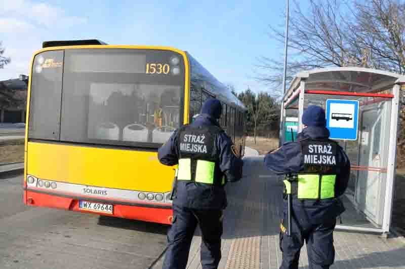 Zdjęcie ilustracyjne: dwóch strażników stojących za autobusem na przystanku.