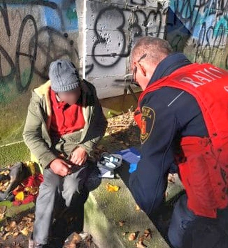 Strażnik miejski udzielający pomocy bezdomnemu mężczyźnie